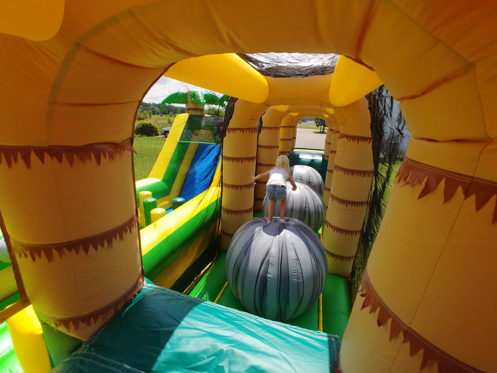 Participant jumping to giant inflatable ball inside obstacle course rental